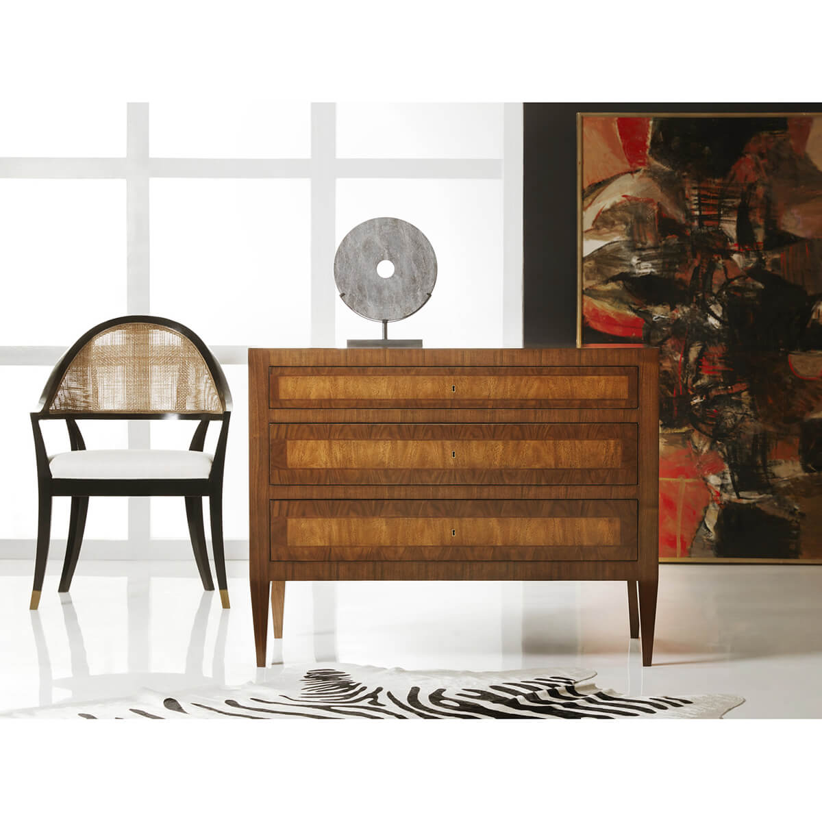 Commode styled with chair and contemporary art piece.