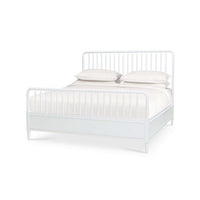 White spindle bed frame with bedding, angled view.