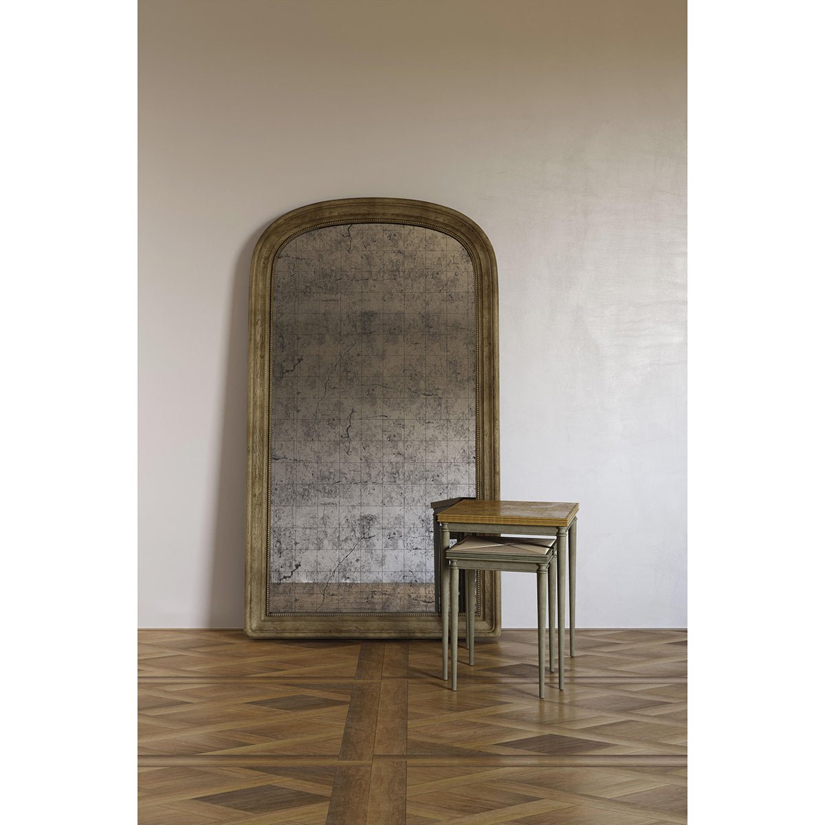 Large antique mirror against wall on wood floor.