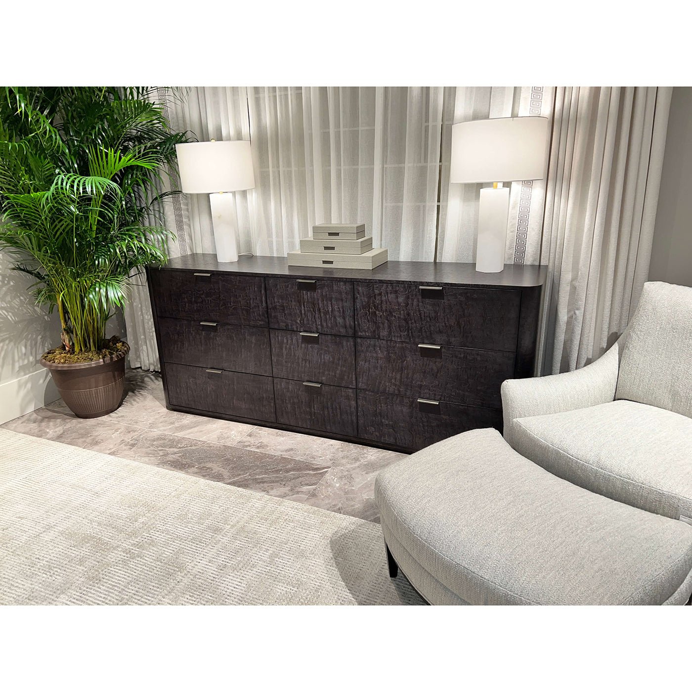 Dresser in living room with lamps and plant.