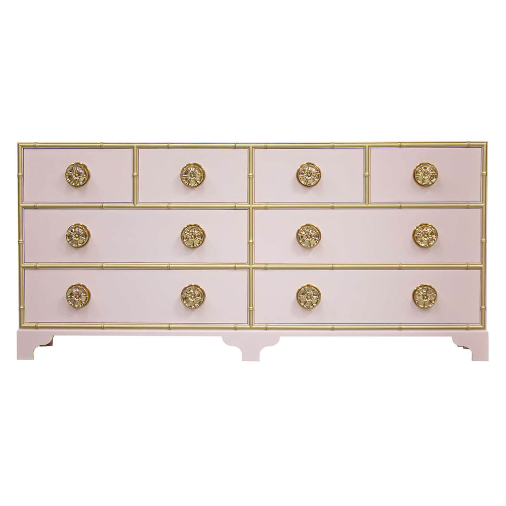 Pink dresser with gold accents and decorative knobs.