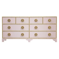 Pink dresser with gold accents and decorative knobs.