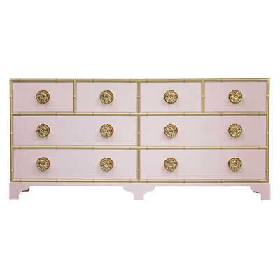 Pink dresser with gold accents and decorative knobs.