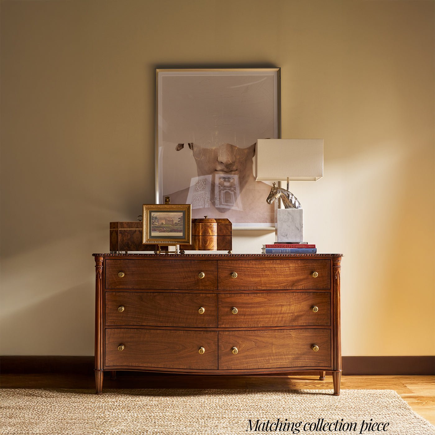 Nightstand in room setting with lamp and pictures on top.
