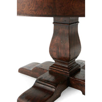 Close-up of table pedestal, dark wood finish.