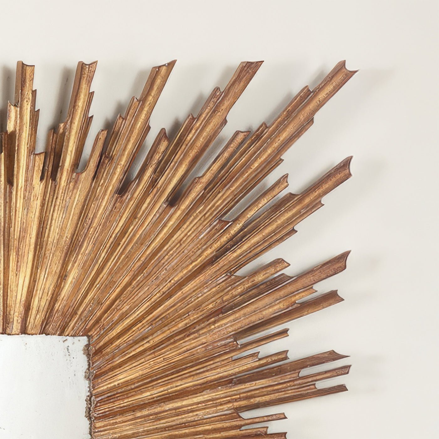 Close-up of gold sunburst mirror frame details, corner view.