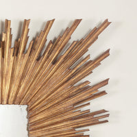 Close-up of gold sunburst mirror frame details, corner view.