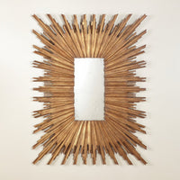 Gold sunburst mirror on white wall, front view.