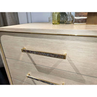 Close-up of dresser drawer handle, light finish.