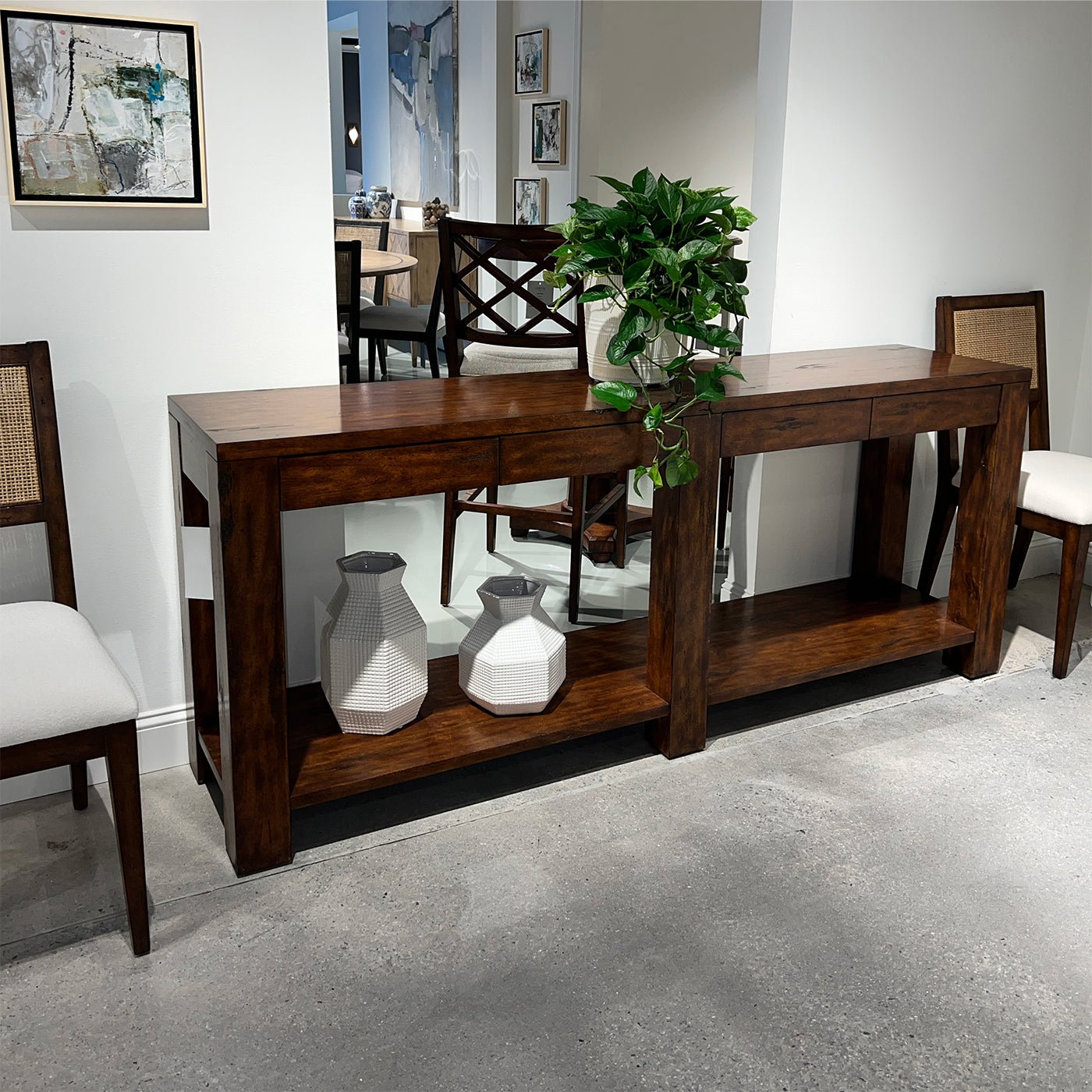 Console table styled with plants and vases in room.