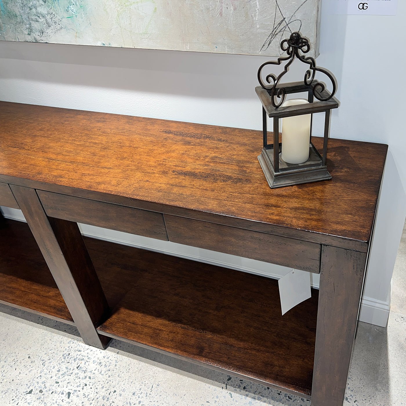 Console table with lantern and art on wall.