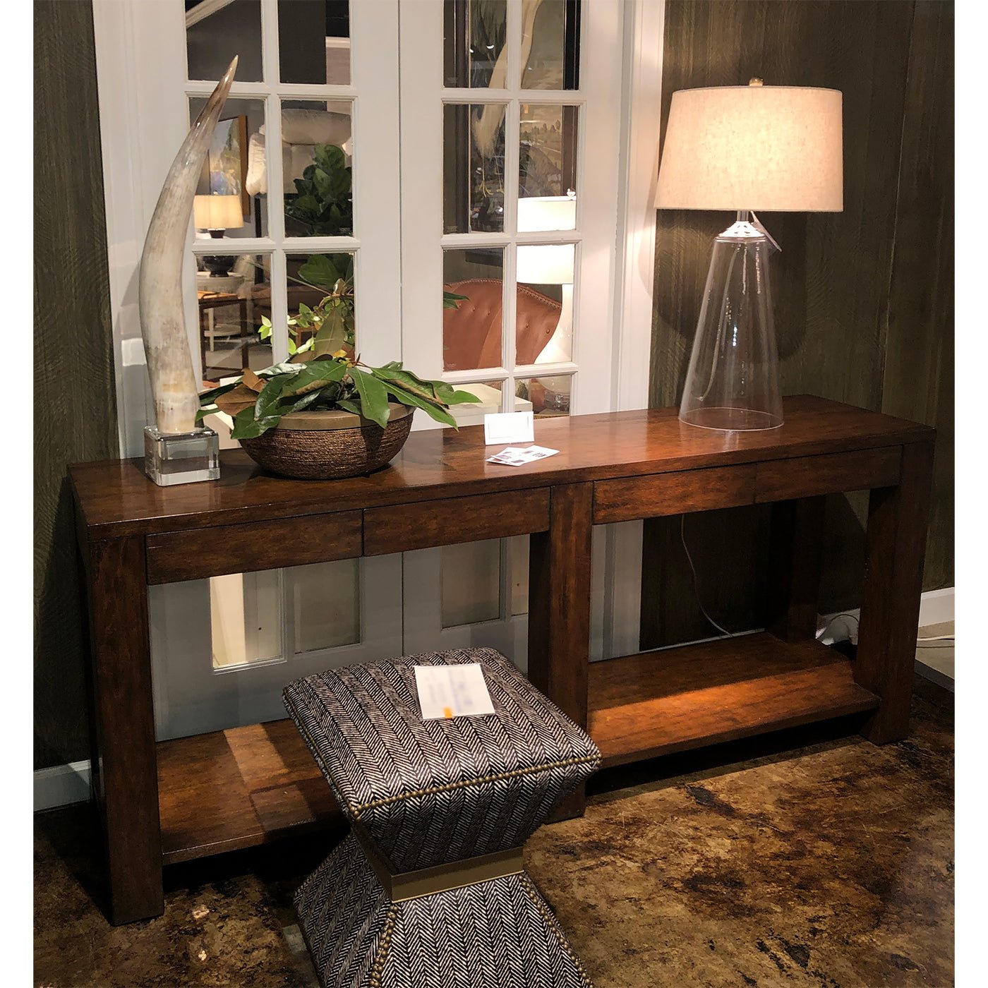 Console table in cozy room with stool and lamp.