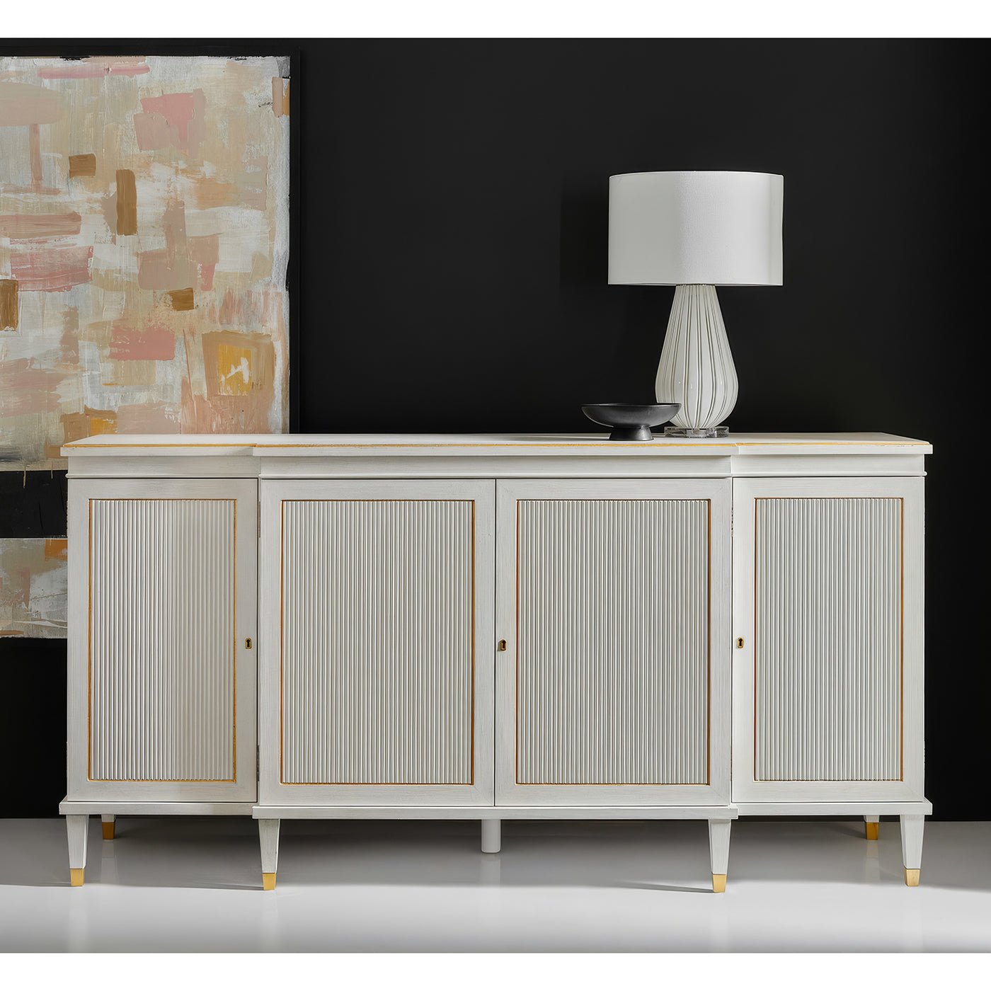 White credenza in styled room, lamp and art above.