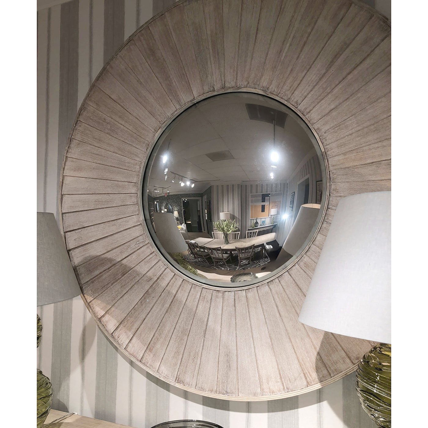 Rustic round mirror reflecting room interior.