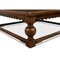 Corner detail of rustic square coffee table, ornate leg design.