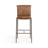 Front view of the slim-frame tan leather bar stool with a padded back, stitched seat and iron footrest