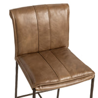 Close-up of the slim-frame tan leather bar stool’s rolled back, decorative stitching and padded seat