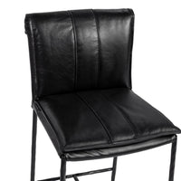 Close-up of the slim-frame black leather bar stool’s rolled back, decorative stitching and padded seat