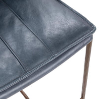 Close-up of the blue leather bar stool’s seat corner, stitching and leather grain