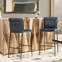 Two slim-frame blue leather bar stools beside a geometric wood-front bar, shown from front and rear