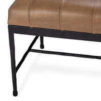 Close-up of the brown leather bench showing a tapered iron leg and low stretcher beneath the channeled seat