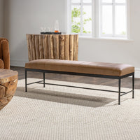 Brown leather bench with a channeled seat and black iron frame on a cream rug beside rustic wood furniture