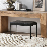 Onyx Black leather bench with a hammered iron base beneath a rustic wood console on a cream rug