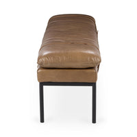 End view of the tan leather bench showing the plump cushion above an upholstered base and black iron legs