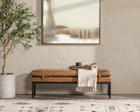 Front room view of the tan leather bench with strap details, a throw and tray beneath abstract artwork