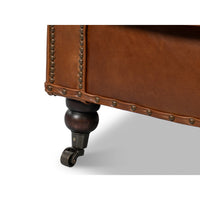 Brown leather club chair, close-up of leg with caster.