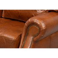 Brown leather club chair, close-up of armrest detail.