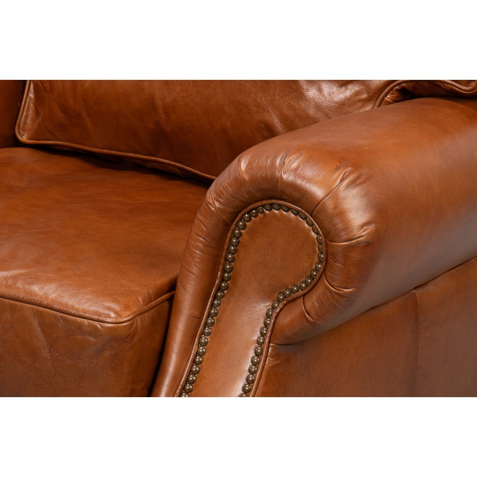Brown leather club chair, close-up of armrest detail.