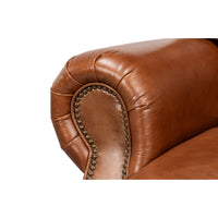 Brown leather club chair, close-up of arm and nailhead.