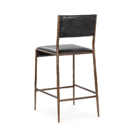 Three-quarter rear view of the black leather counter stool and bronze-toned hammered iron frame