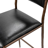 Detail of the black leather seat and back with bronze-toned side supports