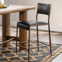 Black leather counter stool beside a wood counter table on a blue and tan rug