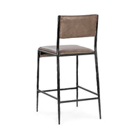 Three-quarter rear view of the taupe leather counter stool with its open back and iron footrest