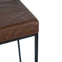 Close-up of the dark brown leather seat corner, stitched seam and black iron frame.