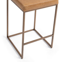 Detail of the tan low-back counter stool’s bronze-toned iron legs, base and footrail.