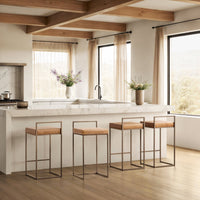 Four tan low-back leather counter stools arranged along a white kitchen island.