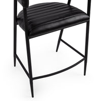 Detail of the channel-stitched black leather seat, tapered iron legs and curved footrest