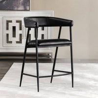 Black leather open-arm counter stool on a pale rug beside a geometric-front cabinet