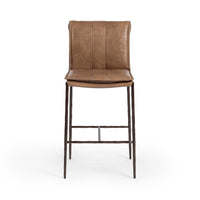 Front view of the slim-frame tan leather counter stool with a padded back, stitched seat and iron footrest