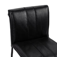 Close-up of the slim-frame black leather counter stool’s rolled back, decorative stitching and padded seat