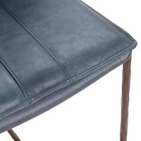 Close-up of the blue leather counter stool’s seat corner, stitching and leather grain