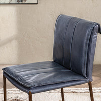 Blue leather counter stool’s stitched seat and rolled back shown close up in a furnished room