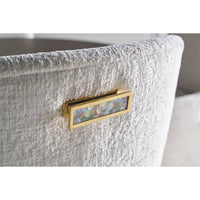 Close-up of armchair's decorative back detail, gold accents.