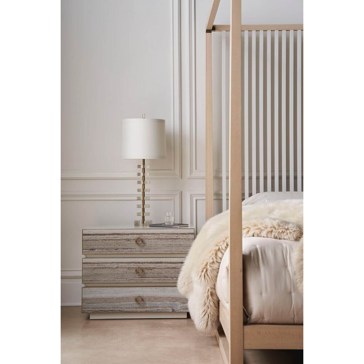 Bedside table next to light mid-century canopy bed.