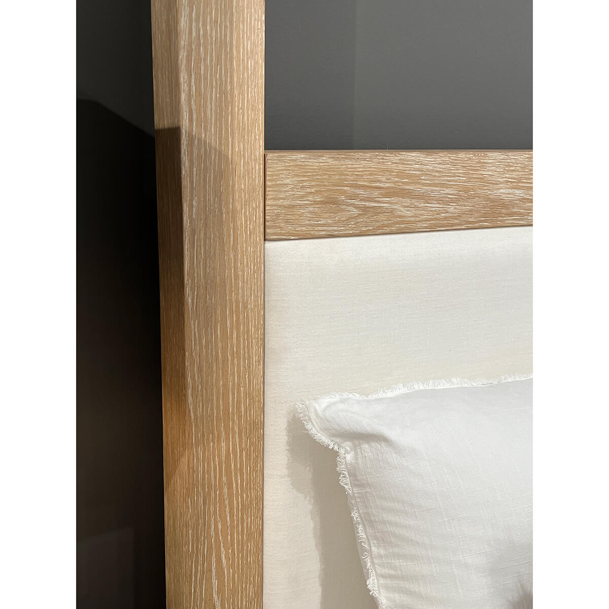 Close-up of light oak canopy bed frame detail.