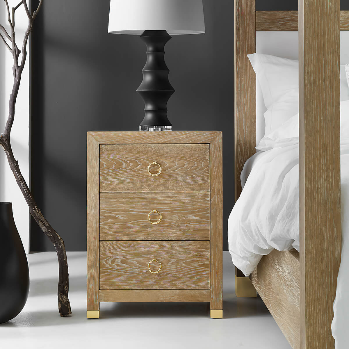 Bedside chest next to bed with lamp on top.